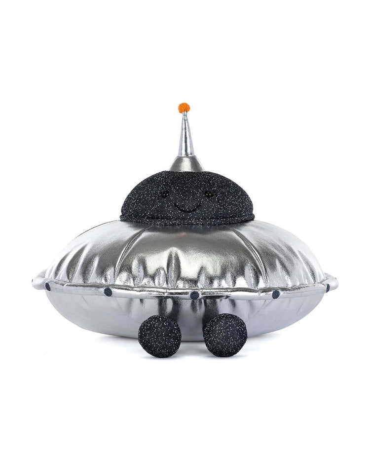 Meet the amuseables jellysaucer by jellycat—a cosmic disco plush shaped like a silver UFO with a smiling, black glittery dome, silver party hat with an orange tip, and black glittery legs.