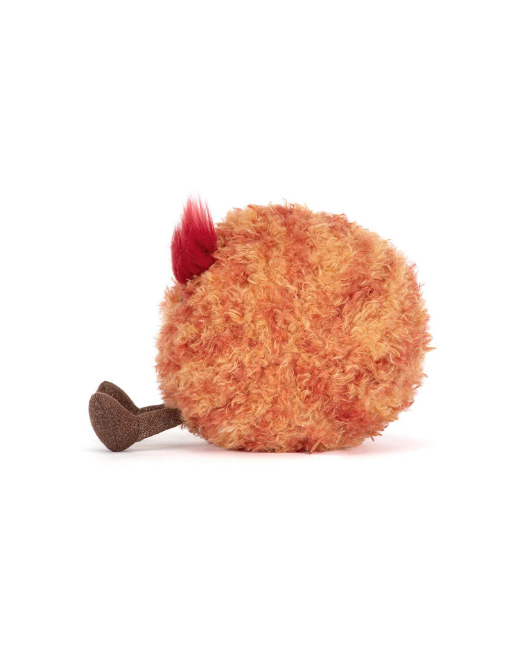A round, fluffy, orange plush toy by Jellycat, with a red tuft and brown drumstick-shaped leg, resembles a cartoon chicken leg and is part of the Amuseables Planet Mars collection.