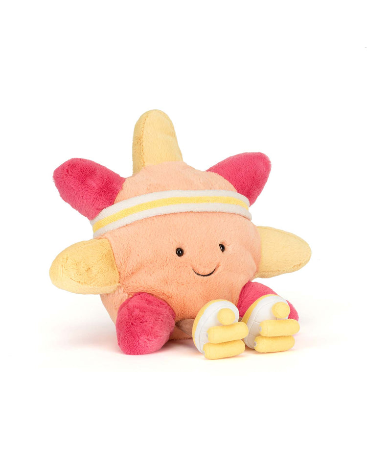 The Jellycat Amuseables Sun Roller Skates is a soft, round plush with orange, yellow, and pink rays, a smiling face, sporty white headband, and yellow-and-white skates—perfect as a cheerful boardwalk toy—displayed on a white background.