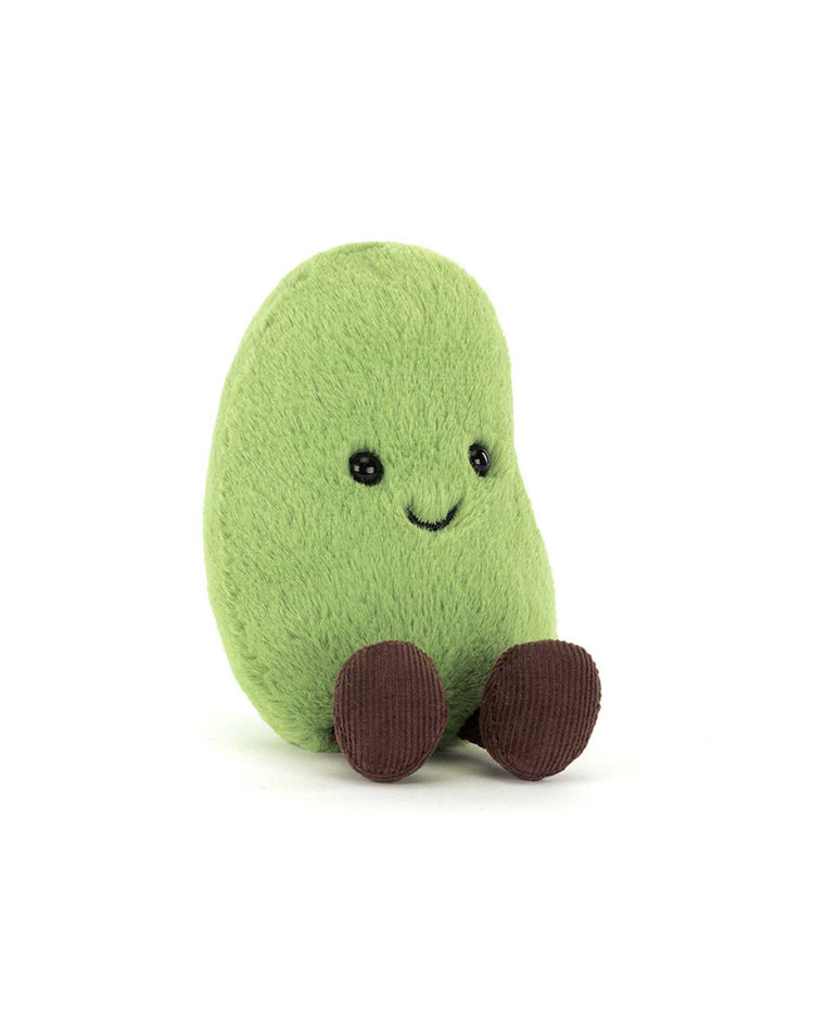 The Jellycat Amuseables Soyella Edamame Bean is a soft, green, bean-shaped plush with a smiling face, black button eyes, and brown corduroy legs and feet, sitting upright against a white background.