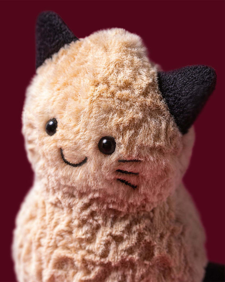 Here’s a rewritten version using your product data: The Jellycat amuseables peanut cat outfit features a plush toy cat with light brown fur, black ears, embroidered eyes, a smiling mouth, and black stitched whiskers. Set against a solid maroon background, this adorable toy is sure to charm in its cute costume.