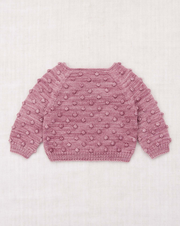 The misha + puff baby popcorn sweater in antique rose, featuring a textured popcorn stitch bobble pattern, long sleeves, and ribbed cuffs and hem, is laid flat on a light neutral background.
