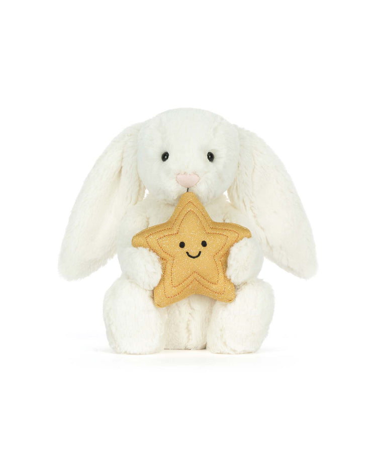 The Jellycat Cream Bunny with Star is an adorable plush toy sitting upright, holding a smiling yellow star pillow—a perfect milestone gift, shown against a plain white background.