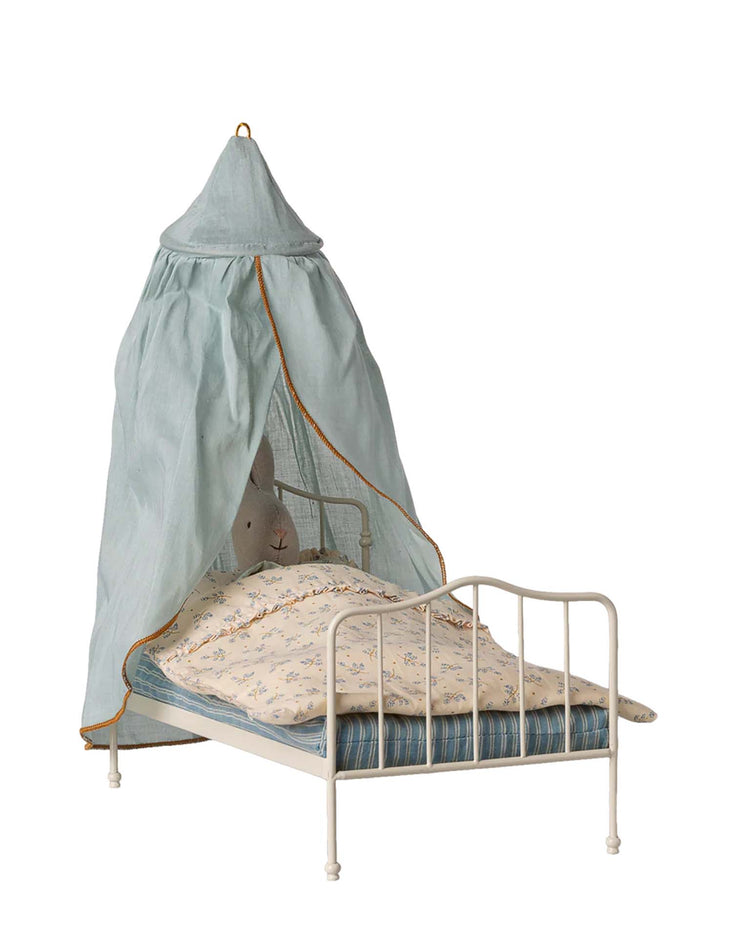 A Maileg miniature bed canopy in mint with gold trim hangs above a small white metal doll bed—perfect for adding charm to any dollhouse or pairing with Maileg accessories.