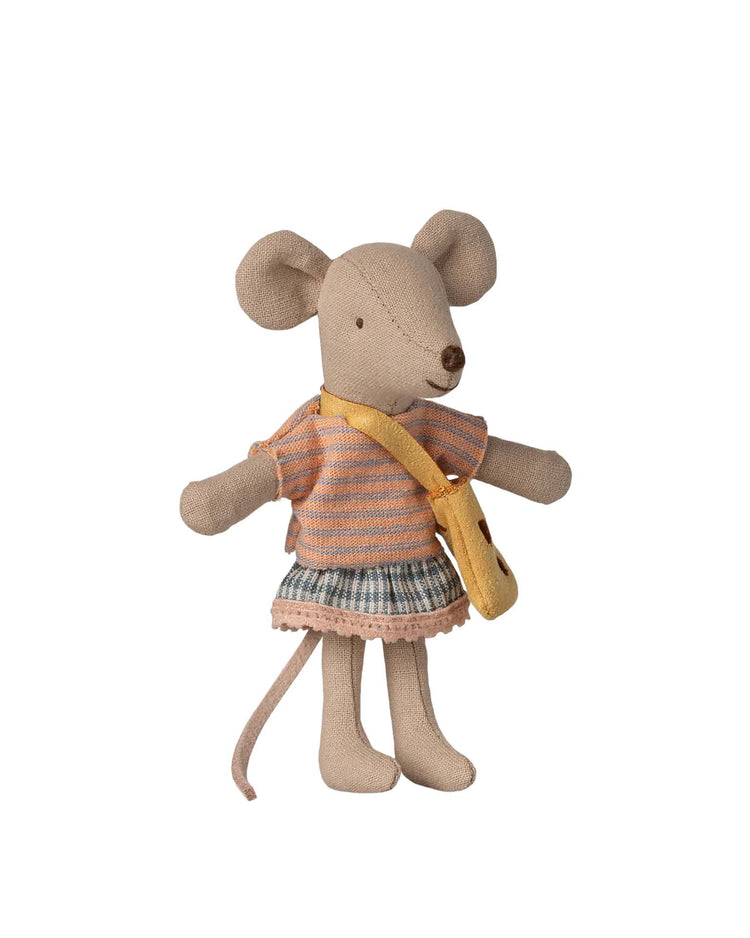 The Maileg little sister mouse with bag stands upright with magnetic hands, wearing a striped shirt, gray skirt, and yellow shoulder bag. This charming fabric mouse features big round ears and a long tail.