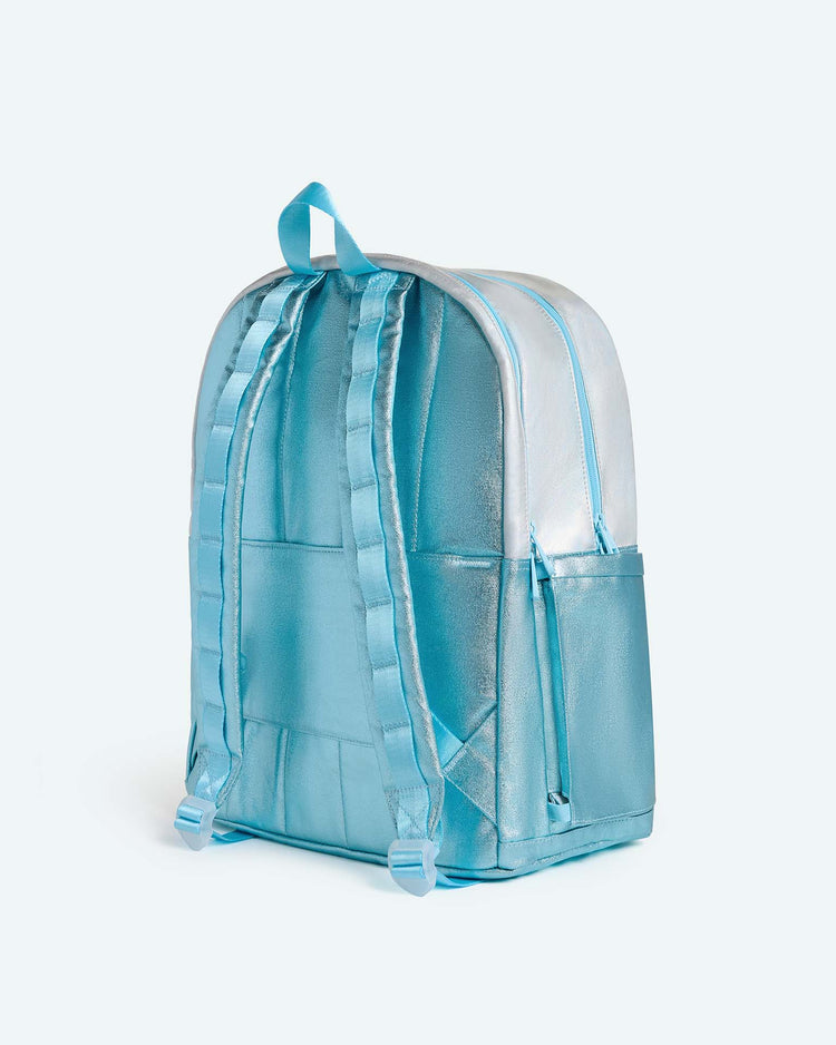 A blue iridescent Kane Large Double Pocket Backpack by STATE Bags features padded shoulder straps, a top handle, and side pockets; shown at an angle to highlight the back and left side—making it a stylish choice for school.
