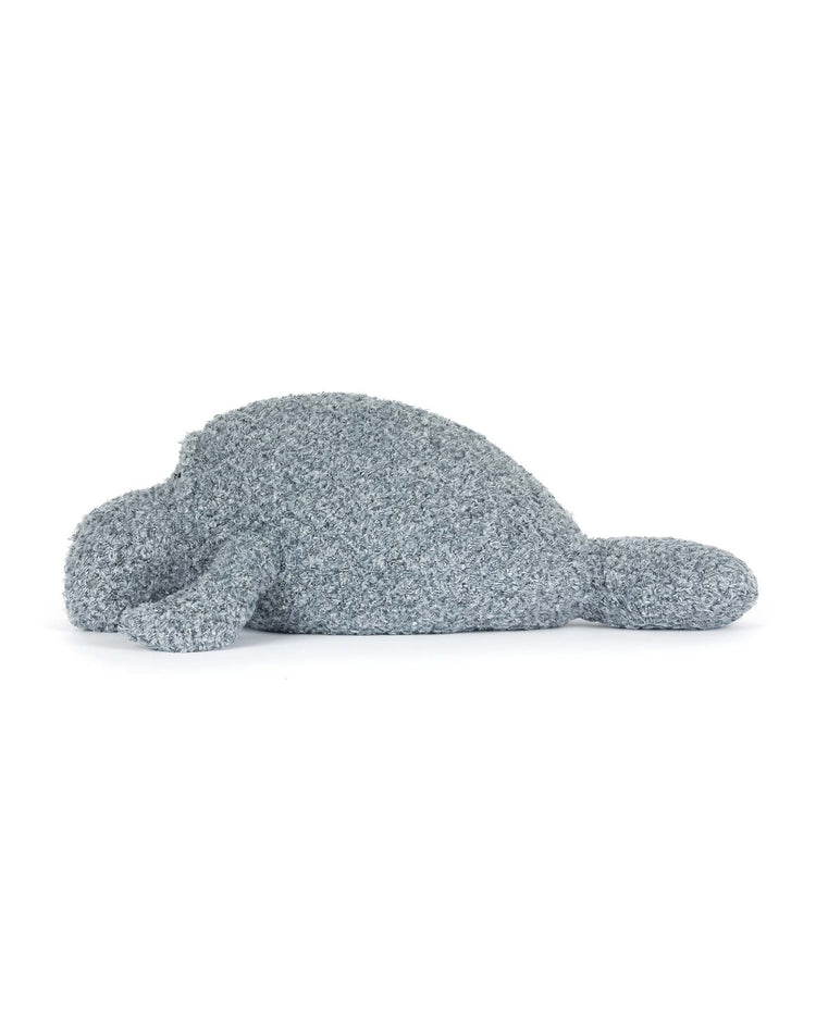 The jellycat maffles manatee is a soft, gray plush toy with minimal features and a slightly textured surface, lying on its stomach against a white background—perfect for those who love cute, ocean-inspired gifts.