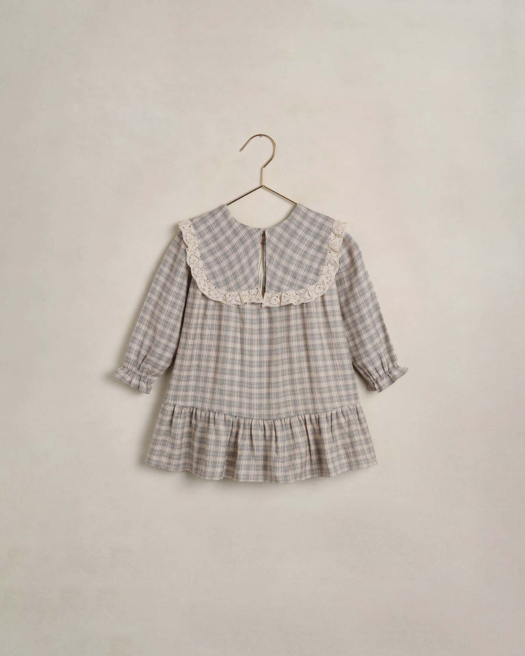 Hanging on a gold hanger against a plain light background, the noelle dress in fall plaid by noralee showcases a large sailor bib collar, ruffled cuffs, and a ruffled hem. This classic long-sleeve dress features delicate lace-trimmed detailing for an effortlessly charming look.