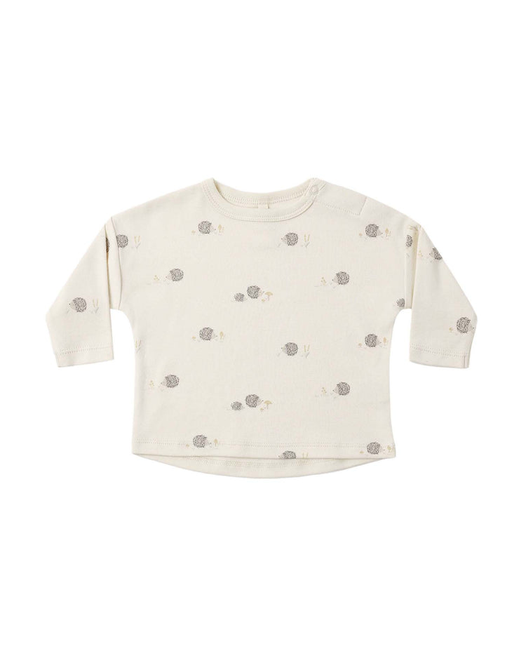 The quincy mae long sleeve tee in hedgehog is a beige organic cotton baby shirt featuring an adorable hedgehog print with minimal plants, designed with a round neckline and handy shoulder snaps for easy dressing. The tee is pictured laid flat on a white background.