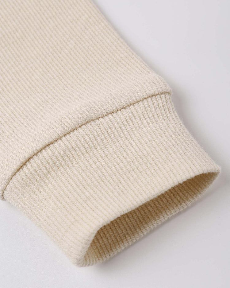 Close-up of the quincy mae ribbed legging in ecru, featuring a cream-colored, stretchy rib knit fabric and a folded cuff, shown on a white background.