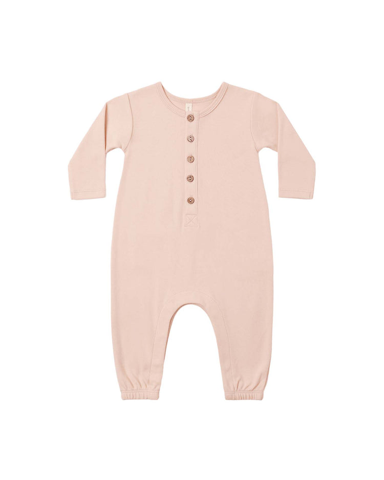 The quincy mae long sleeve jumpsuit in dusty rose, made from soft organic cotton, features five brown buttons down the front and elastic cuffs at the wrists and ankles, shown laid flat on a white background.