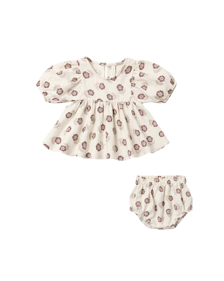 The francy set in fall floral by quincy mae features an ivory baby dress with puffed long sleeves, a gathered skirt, and an empire waist top, all crafted from soft organic cotton. Paired with matching bloomers, both pieces are adorned with a charming purple fall floral print pattern.