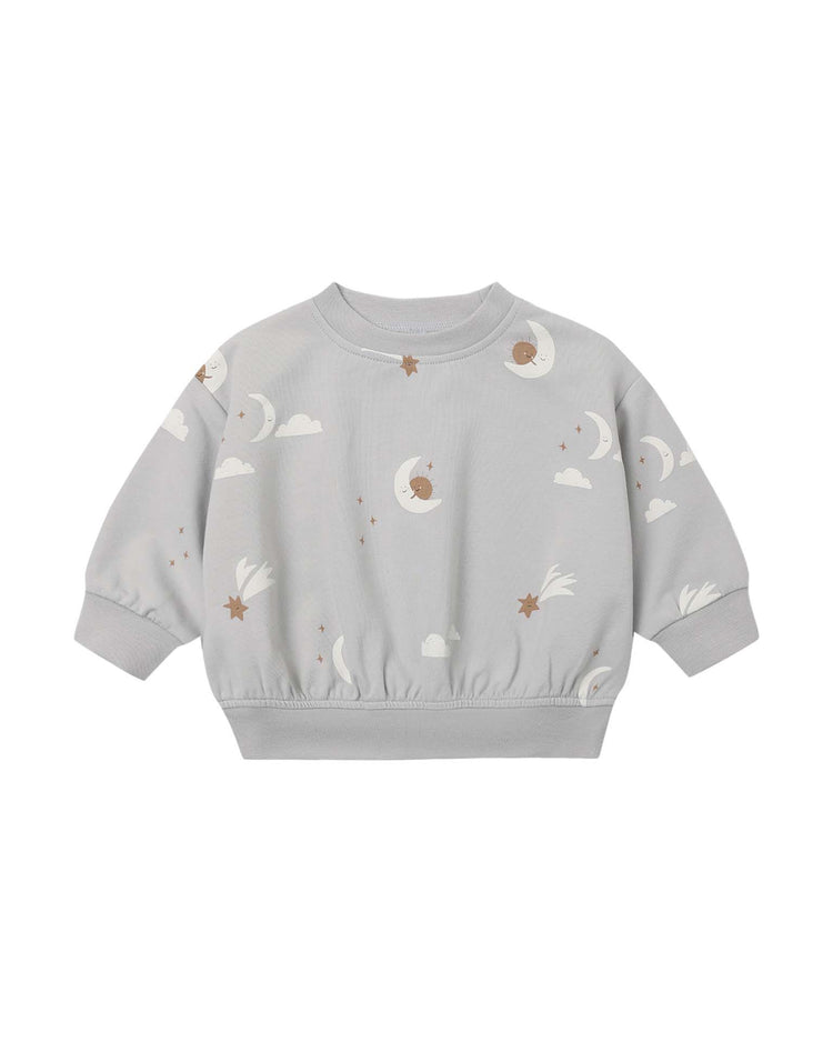 Introducing the relaxed sweatshirt in sky friends by quincy mae—a light grey organic cotton sweatshirt for children, adorned with a playful print of white clouds, crescent moons, brown stars, and comets scattered across the fabric. This cozy piece features long sleeves with ribbed cuffs and hem for extra comfort.