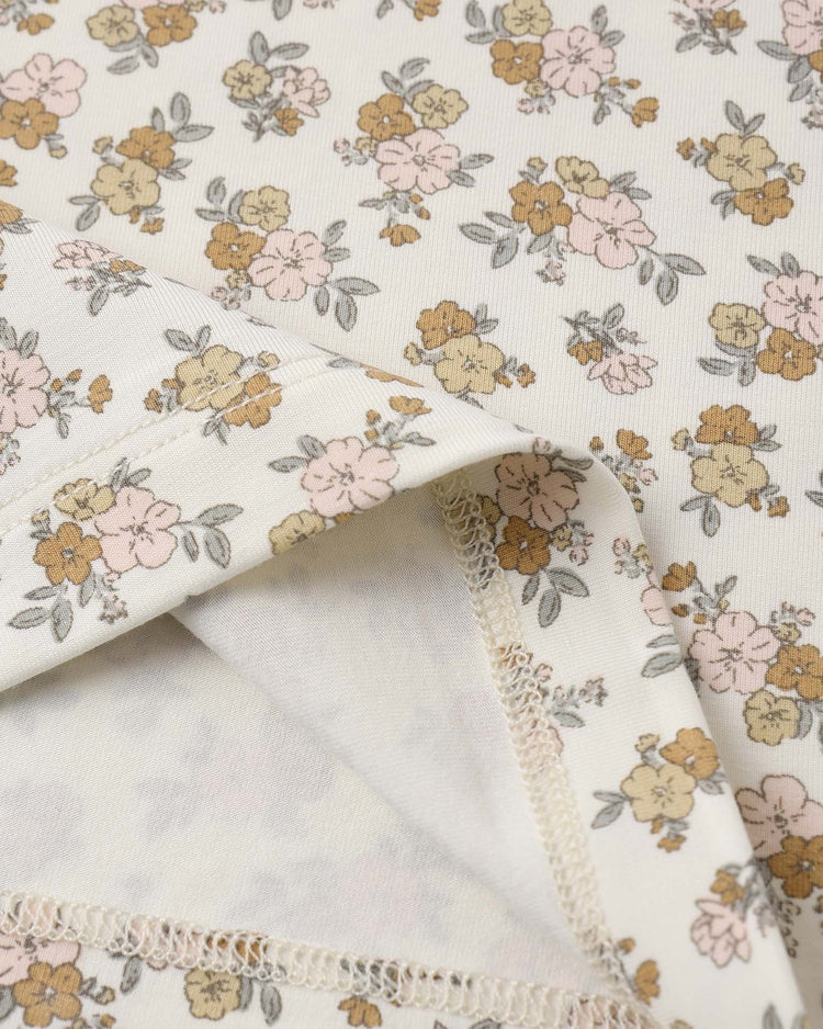 A close-up of the quincy mae bamboo short sleeve pajama set in wildflower, made from soft bamboo fabric and featuring a cream color with a delicate floral print, folded edge, and visible stitching.