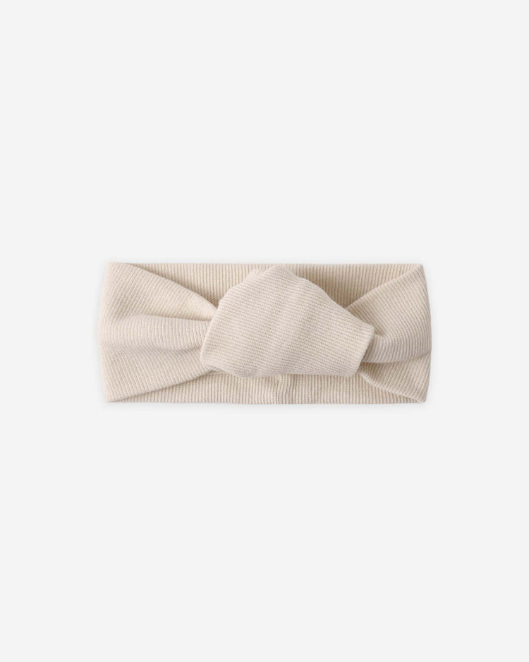 The quincy mae knotted headband in ecru is a ribbed organic cotton baby girl accessory featuring a front twisted knot, shown on a white background.