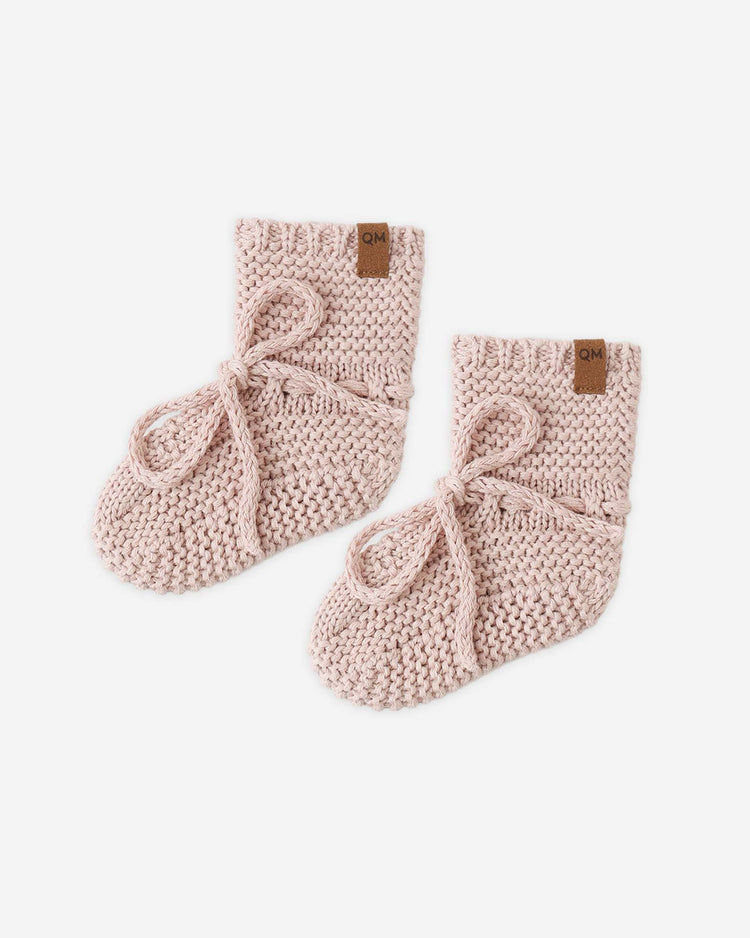 The quincy mae knit booties in blush are soft, knitted baby booties made from organic cotton, featuring tied laces and a small brown tag on each cuff.
