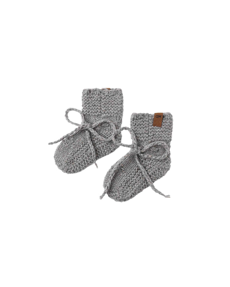 A pair of quincy mae knit booties in heathered slate, featuring cozy cuffs and delicate ankle ties, crafted from soft recycled polyester, are placed side by side on a white background.