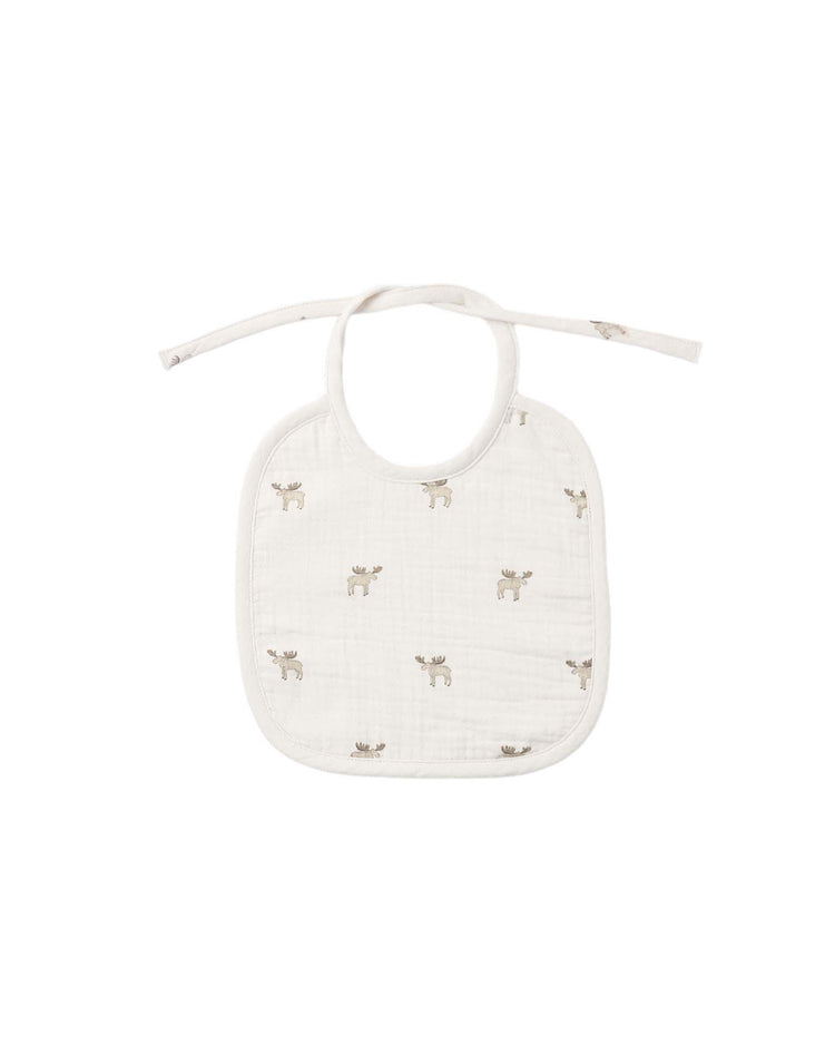 The woven tie bib in moose by quincy mae is a white organic cotton bib adorned with an all-over light brown moose print and features a tie closure at the top.