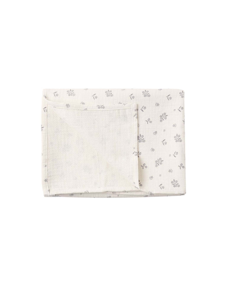 A folded rectangular white cloth, crafted from organic cotton, features a gauze baby swaddle texture and is adorned with small, light gray repeating patterns—possibly bees and leaves—printed across the surface. Rewritten Sentence: The Quincy Mae woven swaddle in winter berry is a folded rectangular cloth made from organic cotton gauze, featuring a soft baby swaddle texture and decorated with delicate, light gray repeating patterns that resemble bees and leaves.