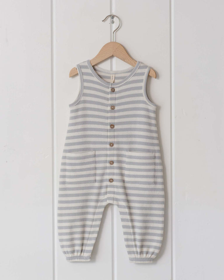 The waffle jumpsuit in sky stripe by quincy mae features a sleeveless design, organic cotton fabric, gray and white stripes, wooden buttons, front pockets, and elastic ankle cuffs—perfect for your baby's transitional wardrobe.