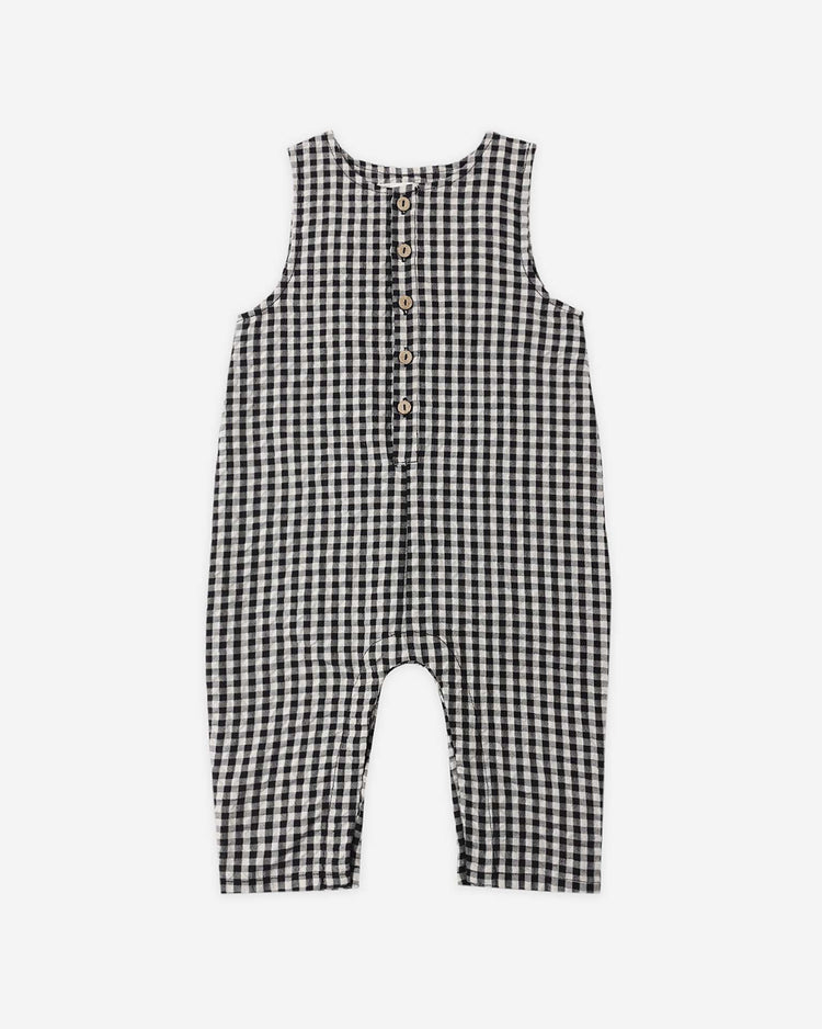 The rylee + cru button jumpsuit in black check is a sleeveless baby outfit with a black and white gingham pattern and five front buttons, shown against a white background.