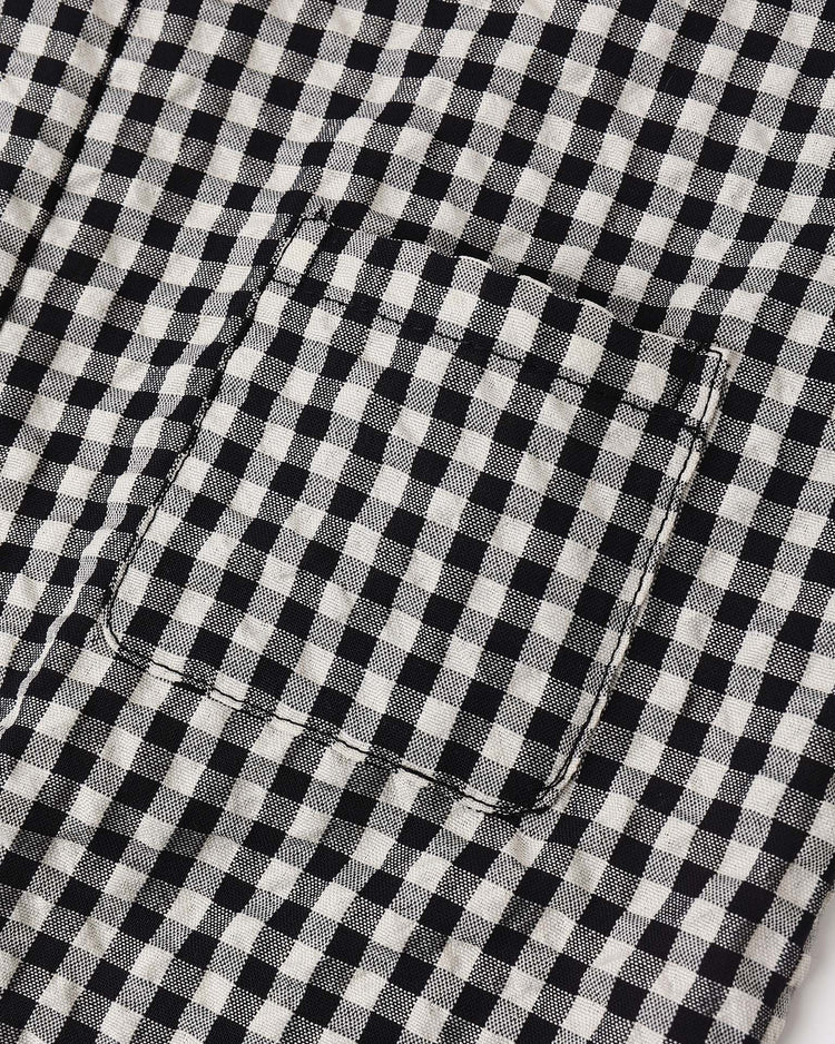 Close-up of a sewn rectangular pocket on the surface of the rylee + cru button jumpsuit in black check, featuring a stylish black and white checkered fabric.