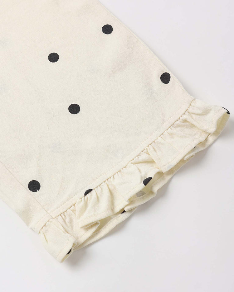 The rylee + cru wide leg pant in polka dot features cream-colored fabric with black dots and a ruffled hem—perfect for a chic look with an elastic waist.