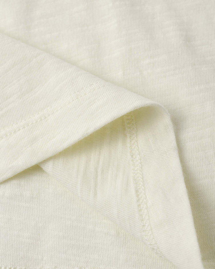 Close-up of the relaxed tee in catch the wave by rylee + cru, featuring light cream cotton jersey fabric with visible texture, detailed stitching, and a neatly folded edge.
