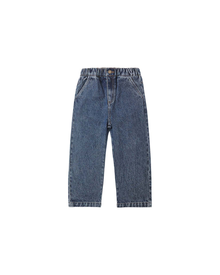The rylee + cru baggy pant in indigo is crafted from 100% cotton and features an elastic waistband and front pockets. Displayed laid flat on a plain white background, these denim blue jeans showcase their relaxed, baggy fit from the front.