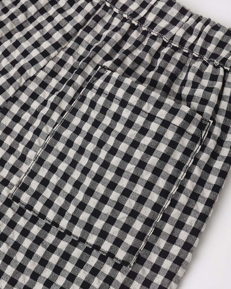 Close-up of rylee + cru's perry short in black check, featuring black and white gingham fabric, a visible pocket, detailed stitching, and an elastic waistband for comfort with a subtle vintage flair.