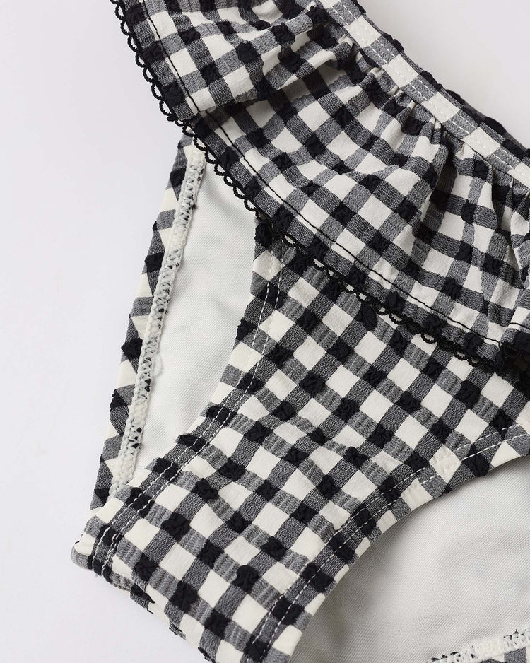 Close-up of the margot bikini in black gingham by rylee + cru, featuring black and white gingham fabric with visible stitching and crochet-style trim, set against a plain white background.