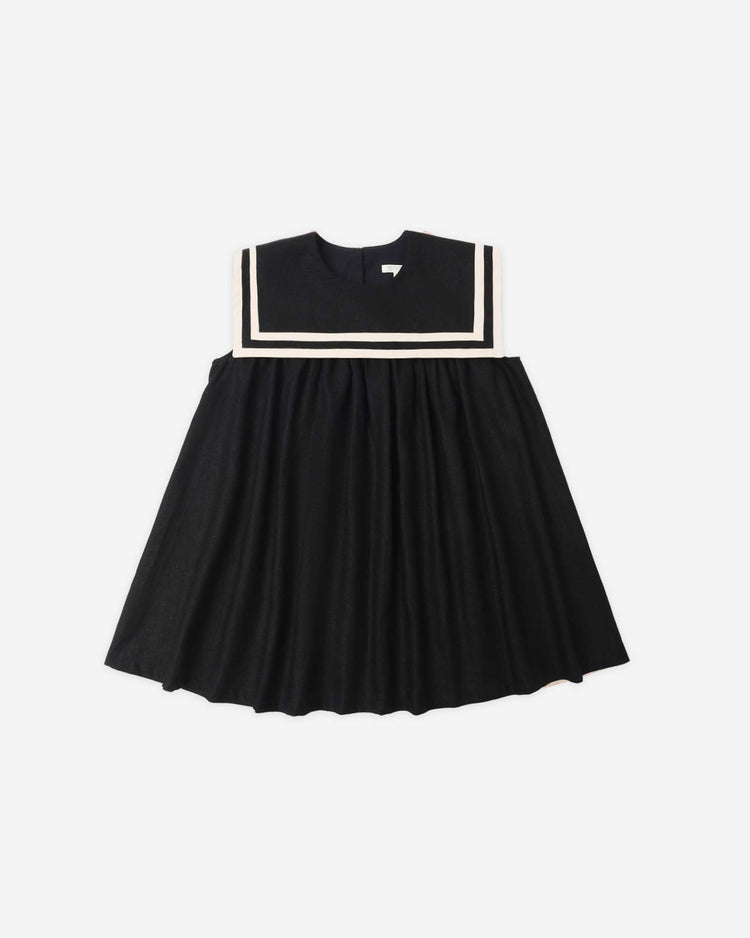 The rylee + cru sailor dress in black is a vintage-inspired, sleeveless children's dress made from black linen viscose, featuring a wide flared skirt and square sailor collar with white trim. Shown laid flat on a white background.