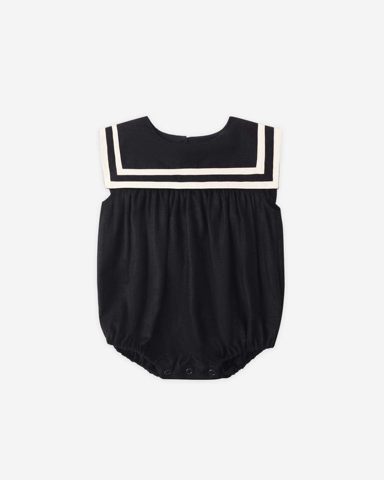The sailor romper in black by rylee + cru is a sleeveless linen baby outfit with a wide sailor-style collar trimmed in white and bottom snap closures—perfect for summer.