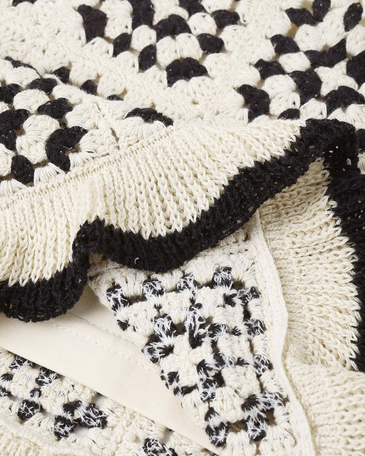 Close-up of textured crocheted fabric from the kira set in abstract by rylee + cru, featuring a black and white checkerboard pattern with scalloped edges—ideal for a chic summer look with its sleeveless top and breezy cotton shorts.