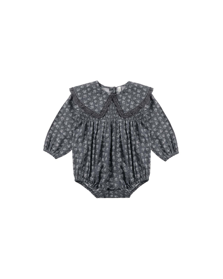 The rylee + cru fern romper in heart ditsy features a gray long-sleeve design with a delicate heart ditsy print, wide crochet lace-trim collar, and elastic cuffs at the wrists and legs.