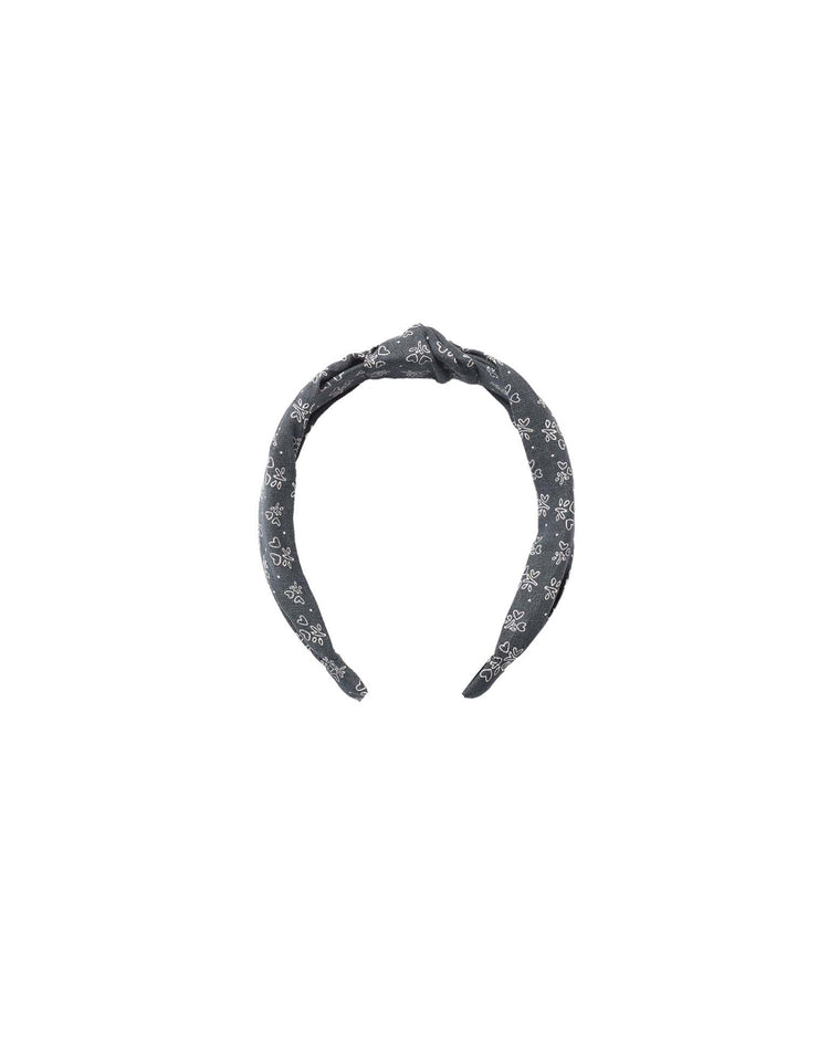 A dark gray “knotted headband in heart ditsy” by rylee + cru, featuring a knot at the top and a subtle white floral pattern, displayed on a plain white background.