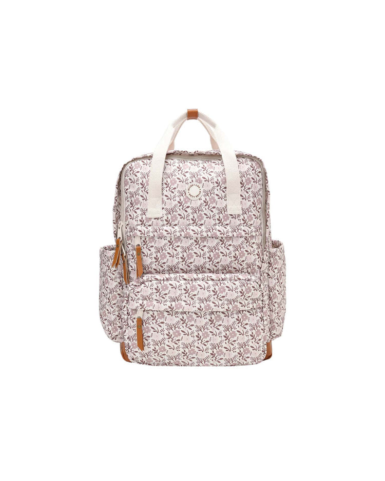 Introducing the backpack in primrose by rylee + cru—a stylish white backpack adorned with brown floral patterns, tan zipper pulls, two side pockets, and white handles. Designed for everyday adventures, it features a spacious main compartment and is showcased against a plain white background.