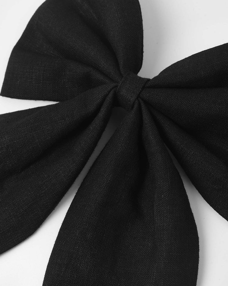 A close-up of the rylee + cru oversized bow in black, featuring four wide linen loops neatly tied and resting on a white surface—perfect as a statement hair clip for elegant styles.