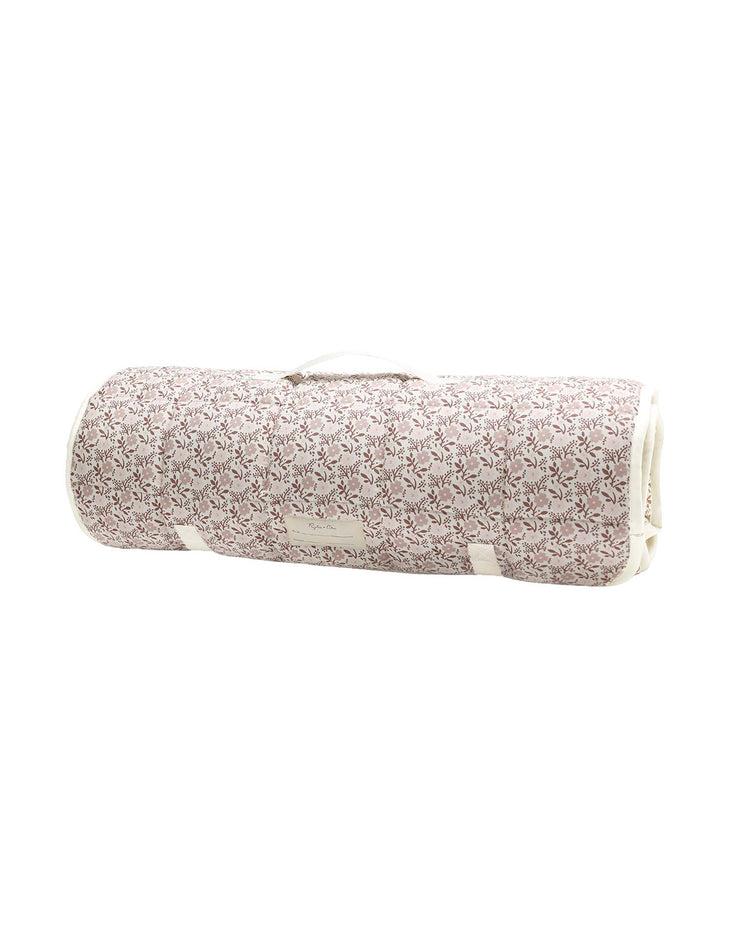 Carry your rylee + cru nap mat in primrose to your next yoga class or relaxation session with this cylindrical, rolled-up bag featuring a pink floral pattern, white trim, and a small handle on top—perfectly sized for transporting your Nap Mat, micro-fleece blanket, or removable pillow.