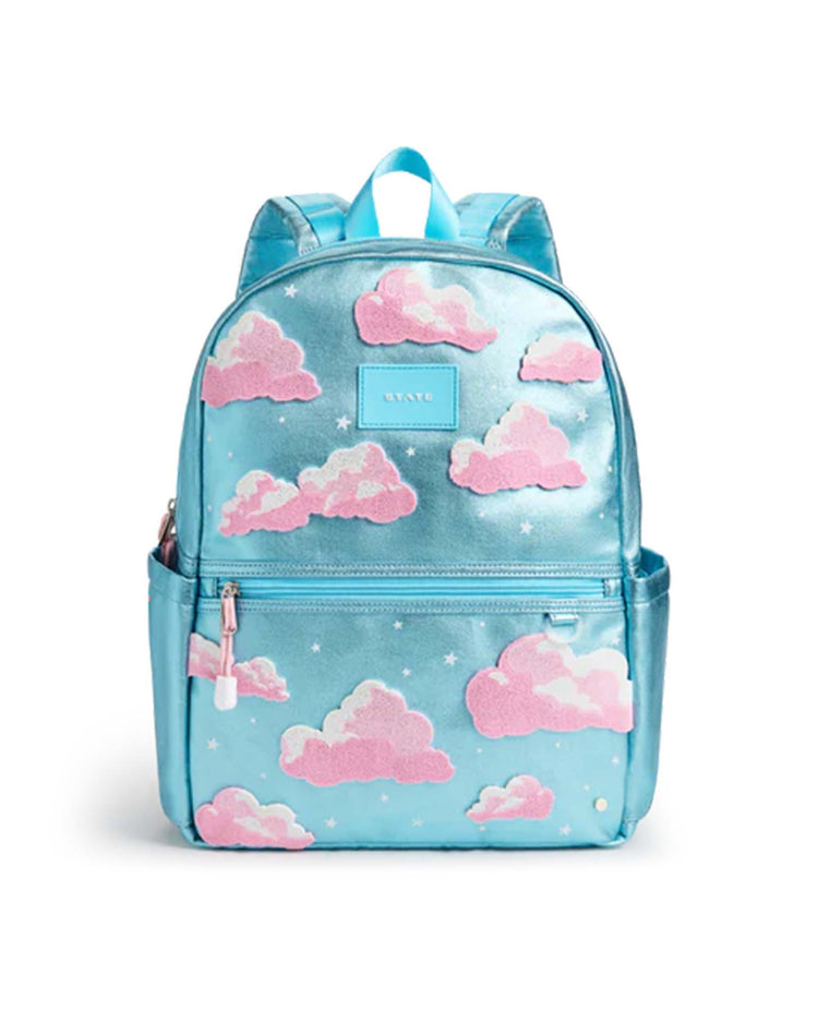 The kane double pocket backpack in clouds by state bags features a shiny blue design with pink and white clouds, small stars, front zipper pockets, matching blue straps, and a convenient top handle—making it a stylish choice for school.