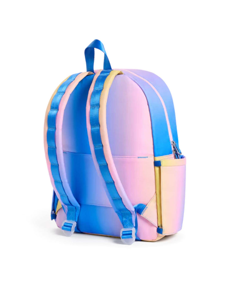 A Kane Backpack in a blue, pink, and yellow gradient from STATE BAGS is shown from the back. This stylish travel backpack features two padded shoulder straps and a zippered side pocket.