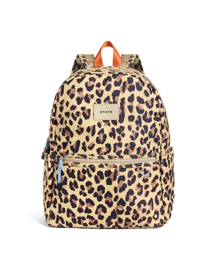 Introducing the Kane Double Pocket Backpack in Leopard by State Bags—a fashionable kids’ school backpack showcasing a tan and black leopard print, two zippered compartments, side pockets, and a brown top handle. Inspired by the beloved State Bags Kane design, this backpack blends playful style with everyday functionality.