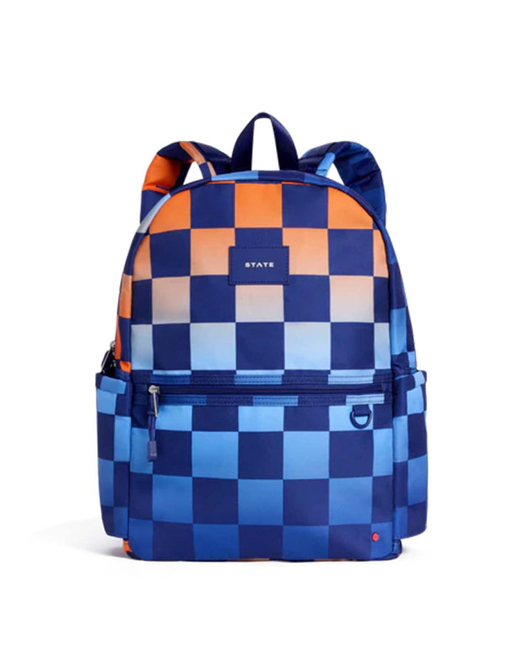 A striking gradient checkerboard pattern in blue and orange gives the STATE Bags Kane Double Pocket Backpack standout style. Designed as the ideal school backpack, it features a front zipper pocket, side pockets, a top handle, and proudly displays the iconic STATE Bags label on the front.