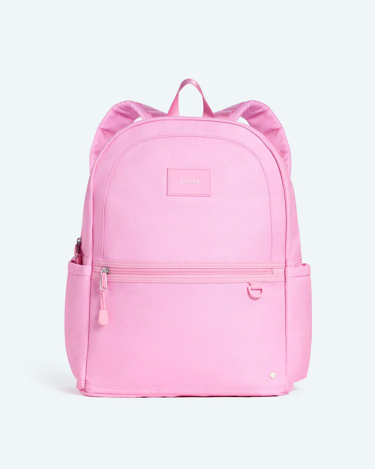 The Kane Large Double Pocket Backpack in Pink by State Bags features a front zipper pocket, top handle, and two padded shoulder straps. Displayed against a plain light background, this backpack is perfect as a stylish school backpack for everyday use.