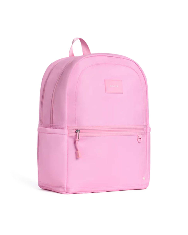 A light pink State Bags Kane Double Pocket Backpack featuring a front zipper pocket, side pockets, and a small top handle is photographed against a white background—perfect for kids to use as a school backpack from the popular State Bags collection.