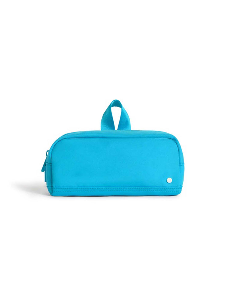 The Clinton Pencil Case in Bright Blue by State Bags is a durable, rectangular case featuring a zipper closure, a small top handle, and a tiny white dot in the bottom corner, shown against a plain white background.