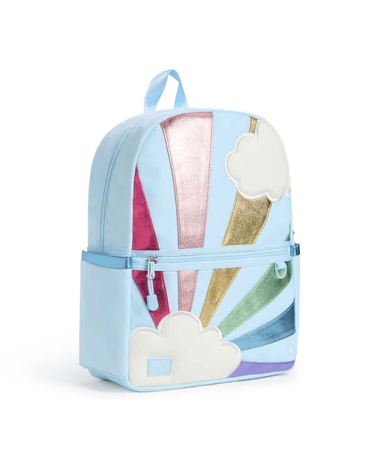 Light blue Kane Backpack in Rainbow Cloud by STATE Bags, featuring metallic rainbow rays, white cloud designs, a front zipper pocket, side pockets, and a top handle—perfect for everyday adventures or as your go-to travel backpack.