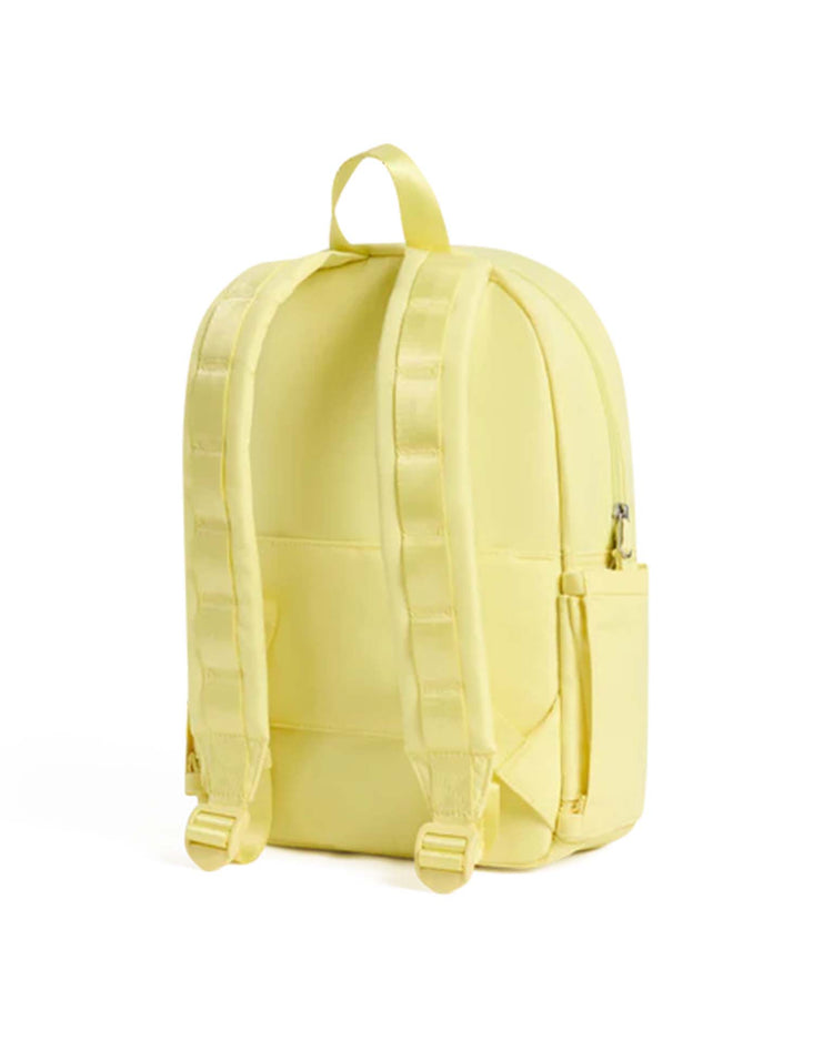A light butter yellow toddler backpack, the Kane Mini Backpack from State Bags, is shown from the back against a plain white background. It features padded shoulder straps, a top carrying loop, a side pocket, and a zipper on one side—combining comfort and style for little ones on the go.