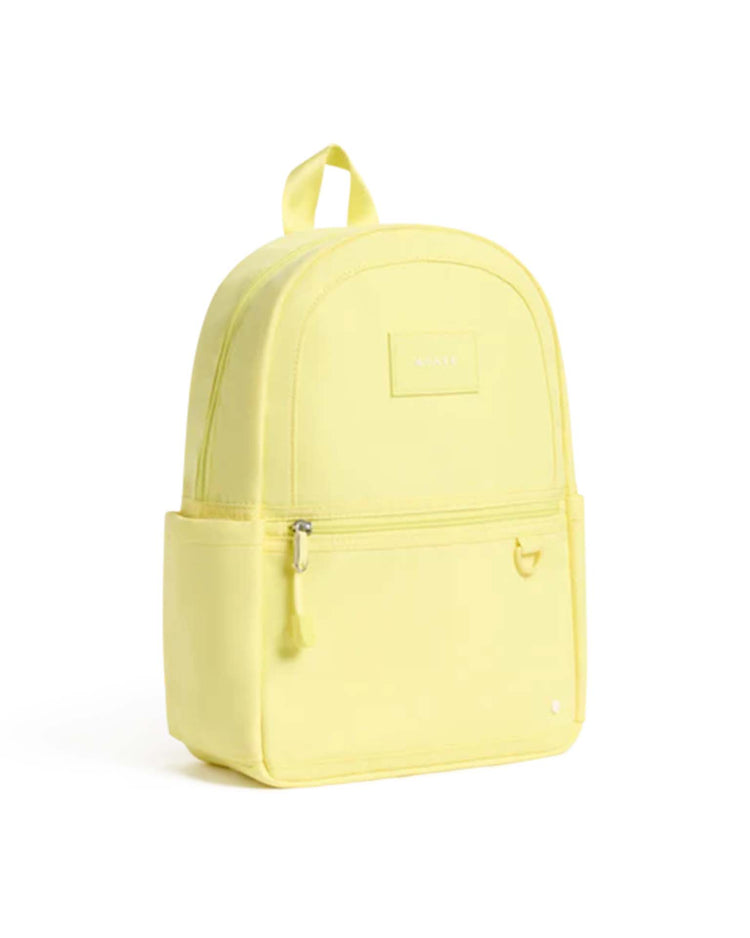 A butter yellow Kane Mini Backpack by State Bags, featuring a front zipper pocket, two side pockets, and a top handle, displayed on a plain white background.