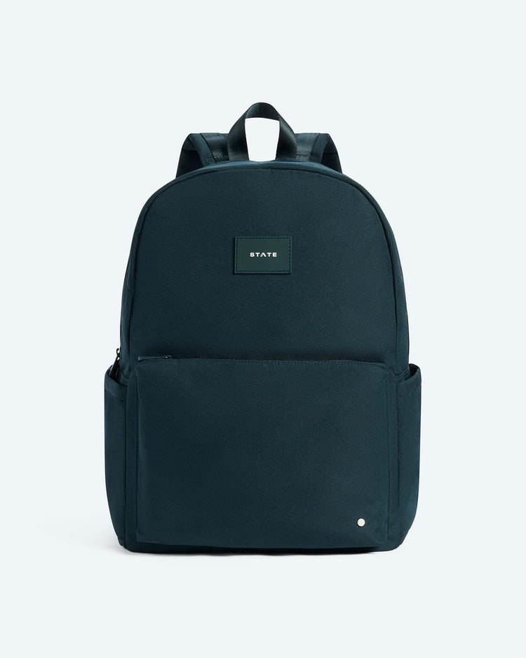 A STATE Bags Reed Backpack in dark green, featuring a front zip pocket, convenient side pockets, and a small rectangular logo patch near the top center, is displayed against a plain light background—making it an ideal choice for a durable school backpack.